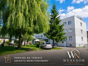 a building with a tree and a car parked in front at 205 Wenedow Noclegi in Koszalin
