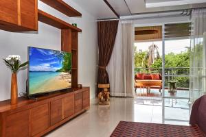 a living room with a flat screen tv on a wooden entertainment center at NB Villa Vimana in Bang Rak Beach