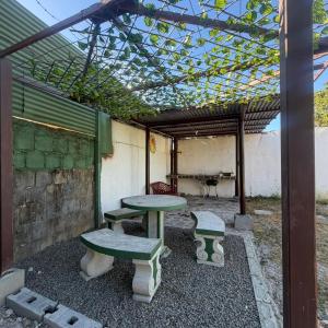 a patio with two tables and benches under a pergola at Mi rinconcito en Liberia in Liberia