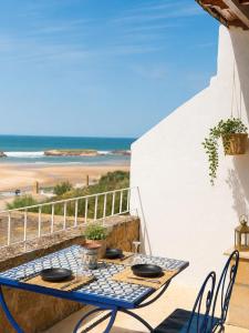 a table on the balcony with a view of the beach at Le petit château Vue sur mer Uniquement les familles in Oualidia