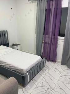 a bedroom with a bed with purple curtains at Winner house in Oran