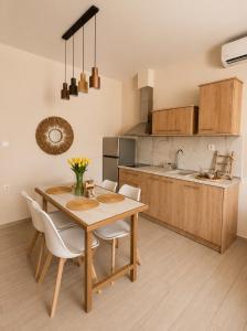 eine Küche mit einem Holztisch und weißen Stühlen in der Unterkunft Salvatore in Sykia