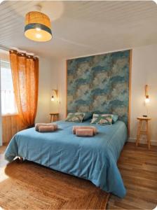 a bedroom with a blue bed with a painting on the wall at Le Clos de Saint Georges in Saint-Georges-dʼOléron