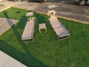 three chaise lounges and a chair on the grass at GuestHouse Relax & Pool in Esmoriz