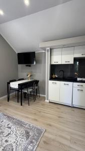 a kitchen and dining room with a table and white cabinets at Domki na Wesołej 2 in Połczyno
