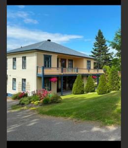 a large house with a balcony on a lawn at Cabines Boréales et Maison de chambres in Rimouski