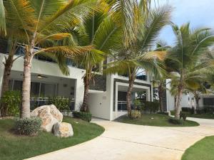 a house with palm trees in front of it at Estrella Garden Condos con Vista a la piscina in San Rafael del Yuma