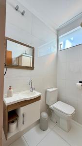 a bathroom with a toilet and a sink and a mirror at Espaço Primavera in Pouso Alegre