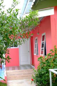 una casa roja con una puerta blanca y un árbol en Ban Suan Lung Rin en Kanchanaburi