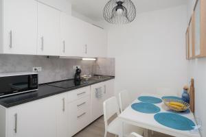 a white kitchen with a table with blue plates on it at B-Two10 in Balatonlelle