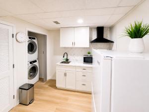 a kitchen with white cabinets and a washer and dryer at Elegant Boutique Stay in Lilburn