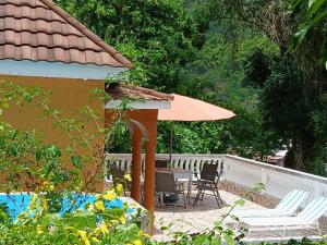 a patio with a table and chairs and an umbrella at Skyview Palace in Morant Bay