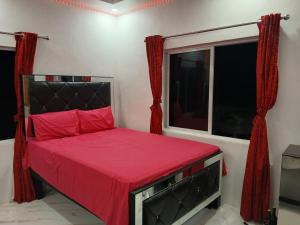 a bedroom with a bed with red sheets and a window at Skyview Palace in Morant Bay