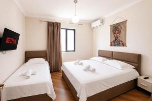 two beds in a hotel room with white sheets at Villa Reve de Tirana in Tirana