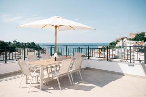 a table and chairs with an umbrella on a balcony at Laz Palace in Ulcinj