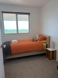 a bedroom with an orange bed with a window at Carters Beach Escape in Carters Beach