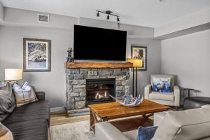 a living room with a fireplace with a flat screen tv at Rocky Mountain Condo with views of Grotto Mtn and hot tub in Dead Man's Flats