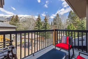 a balcony with a red chair and a table at Rocky Mountain Condo with views of Grotto Mtn and hot tub in Dead Man's Flats