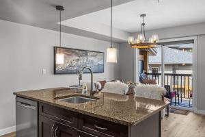 a kitchen with a sink and a living room at Rocky Mountain Condo with views of Grotto Mtn and hot tub in Dead Man's Flats