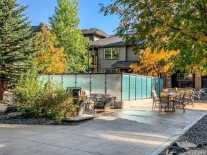 a house with a fence and tables and chairs at Rocky Mountain Condo with views of Grotto Mtn and hot tub in Dead Man's Flats