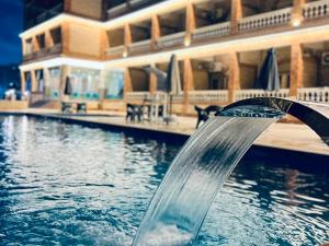a pool with a water fountain in front of a building at La mer Hotel in Alexandria