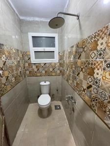 a bathroom with a toilet and a window at Vrtn home in Al Ghuşnah