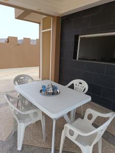 a white table with white chairs and a tv at Résidence Zaouit Aglou in Aglou