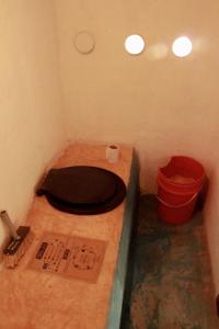 a bathroom with a toilet and a red bucket at Espacio Circular Eco Hostel in San Marcos Sierras