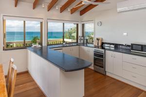 a kitchen with white cabinets and a view of the ocean at Lawsons at Blueys in Blueys Beach