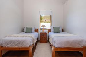 two twin beds in a room with a window at Lawsons at Blueys in Blueys Beach