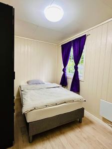 a bedroom with a bed and a window with purple curtains at Apartment in Måløy in Måløy