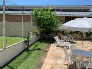 a patio with a table and chairs and an umbrella at Studio 1202 Confortável, Piscina e próximo a praia! in Guarujá