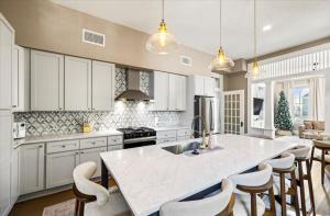 a kitchen with white cabinets and a large island with bar chairs at Sand and Sea Manor in Galveston