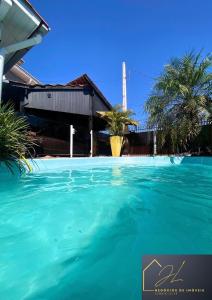 a pool of blue water in front of a house at 10 - Casa completa com piscina, Wi-Fi e Garagem in São Leopoldo