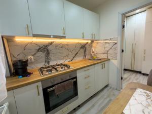 a kitchen with white cabinets and a stove top oven at Luu's Studio! in Hunedoara +2 photos