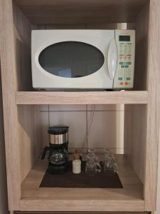 a microwave sitting on top of a shelf with a coffee maker at Apartamento com sacada, estacionamento e piscina in São Leopoldo +1 photo