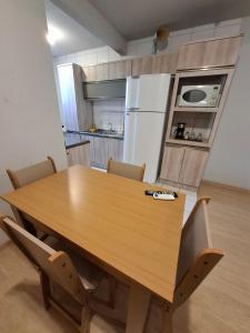 a dining room table with chairs and a kitchen at Apartamento com sacada, estacionamento e piscina in São Leopoldo