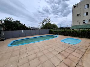 a swimming pool in a yard with a building at Apartamento com sacada, estacionamento e piscina in São Leopoldo