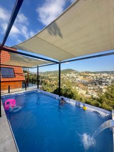 a swimming pool with a canopy and a person in the water at أكواخ المها oryx cottage in Ajloun