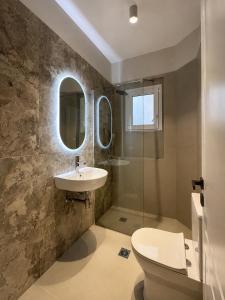 a bathroom with a sink and a toilet and a mirror at Angelland Luxury Suites in Nafpaktos +22 photos
