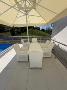 a patio with a table and chairs and an umbrella at Luksuzna kuća sa bazenom in Modriča