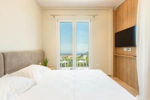 a bedroom with a white bed and a television at New Dhermi Icon 3 - Parking in Dhërmi