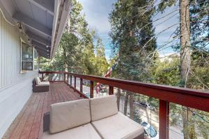 a balcony with a couch and a view of trees at Idyllic Cabin in the Woods: Cozy Crestline Retreat in Arrowhead Highlands