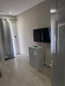 a room with a small refrigerator and a television on the wall at The Gardens view lodge in Bushbuckridge