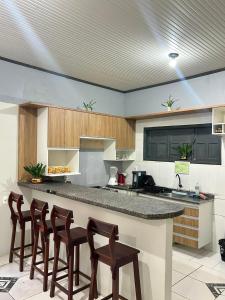 a kitchen with a counter with four bar stools at M&A Hospedagem in Cruzeiro do Sul