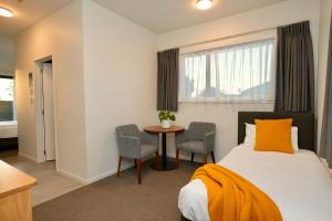 a bedroom with a bed and a table and chairs at Yates Park Motel in Auckland