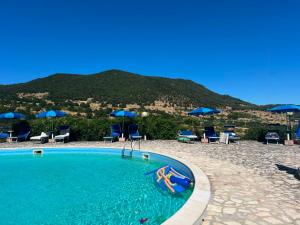 a swimming pool with chairs and umbrellas and a mountain at Agriturismo Monte Sacro in Mattinata