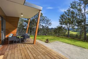 a house with a deck with a view of a yard at Hudsons Hideaway - Cosy Eco Cabin, Rainforest Walks in Dorrigo