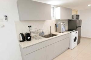 a white kitchen with a sink and a dishwasher at Barak Royal Suites 20 sea view - ג'קוזי בחצר ומרפסות עם נוף לים in Eilat