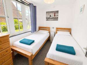 two beds in a room with two windows at Cornwall Cosy Bungalow in Hayle +7 photos